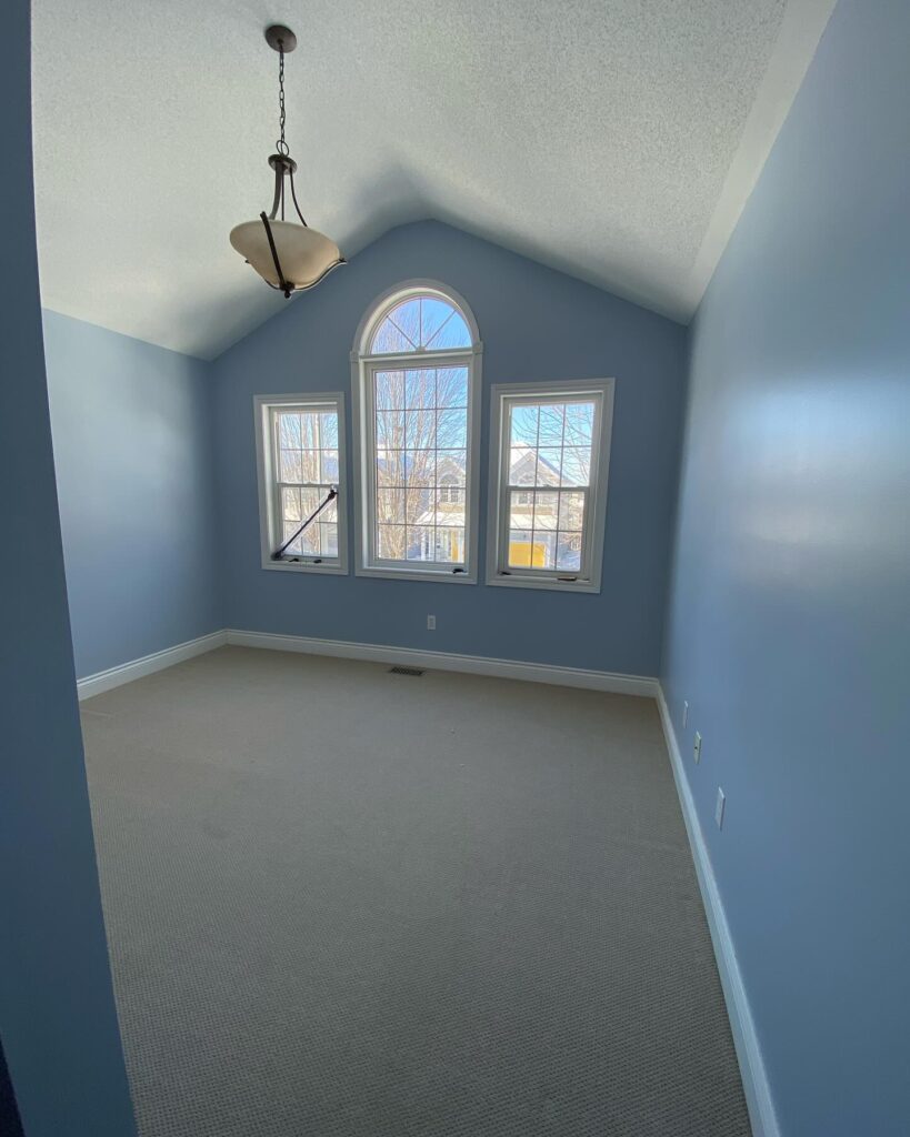 A professionally painted bedroom in Ottawa with a vaulted ceiling and bold blue walls.