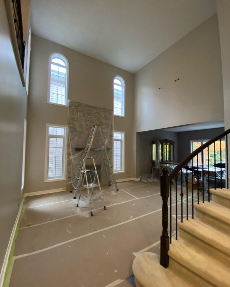 Extensive surface preparation for living room painting Ottawa with vaulted ceilings and stone fireplace.
