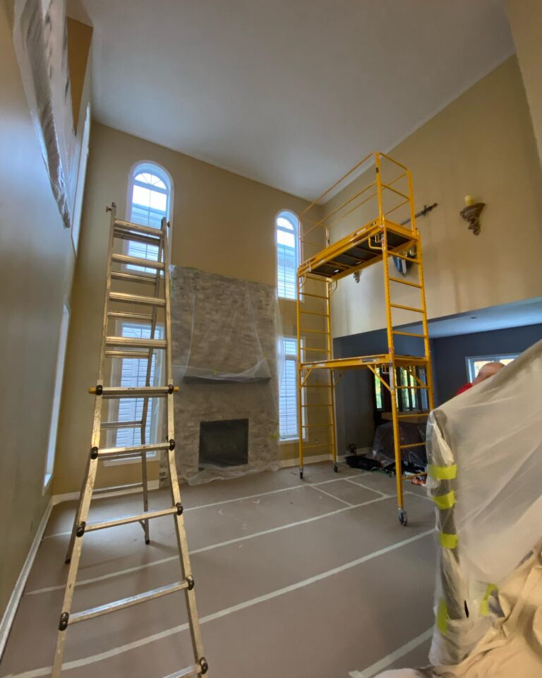 Professional painters using scaffolding for high ceiling painting Ottawa projects in a large living room.