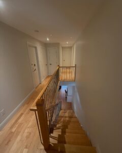 Freshly painted hallway and staircase in an Ottawa home, featuring light neutral walls and hardwood floors.