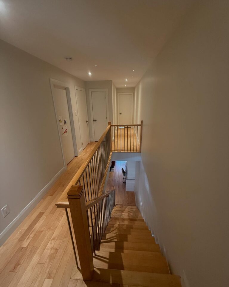 Freshly painted hallway and staircase in an Ottawa home, featuring light neutral walls and hardwood floors.
