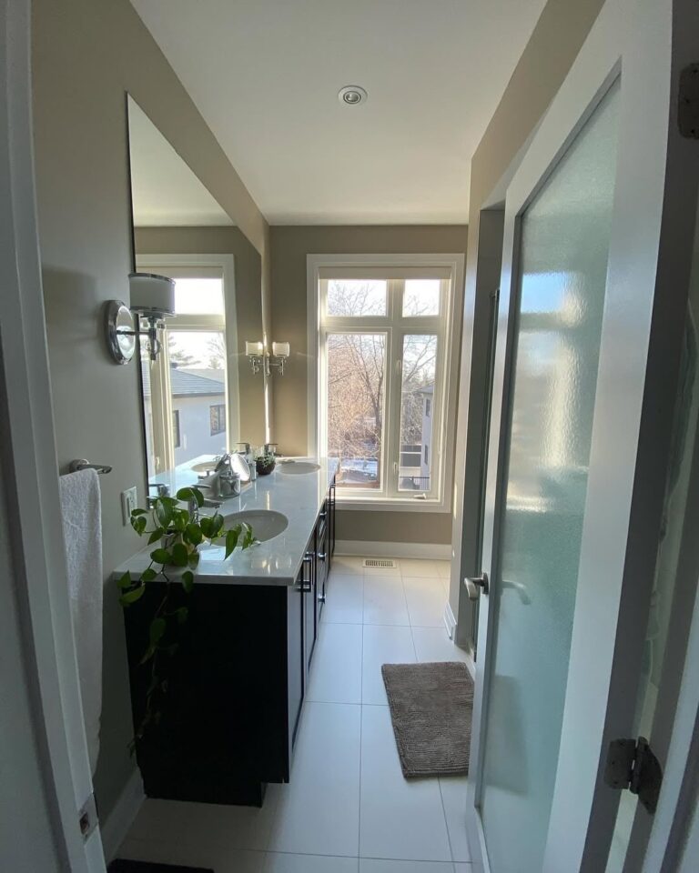 Modern bathroom with glass shower and grey tile painted in a clean white finish.