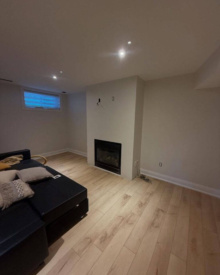 Professional basement painting Ottawa project featuring a modern fireplace and clean neutral walls.