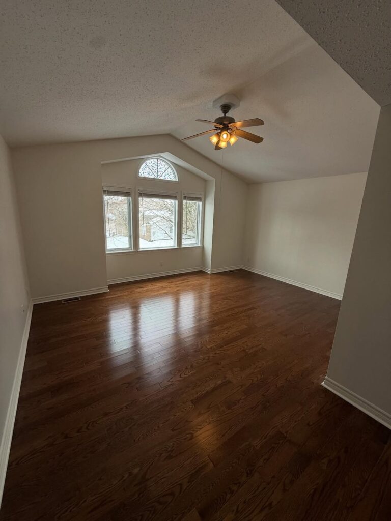 Residential painting Ottawa master suite with vaulted ceilings, ceiling fan, and arched windows.